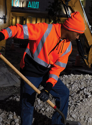 A man wearing a neon orange hoodie, digging with a shovel.